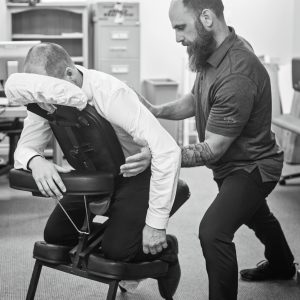 Massage therapist assisting client in a clinical setting. Promotes wellness and workplace health.