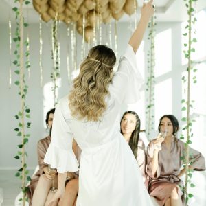 Bride and bridesmaids enjoy a celebratory toast with champagne indoors.